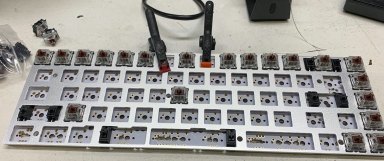 The plate clamped to the PCB, with some switches already installed